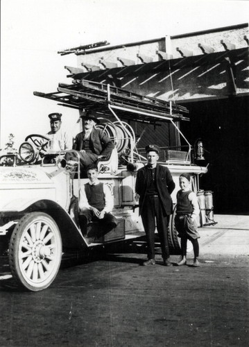 “Bugs”, Mr. Hyatt, Fire Chief George Sanven, and Billie Mahu with 1916 Seagraves triple combination pumper in front of Coronado fire station located on 6th at Orange Avenue, Coronado, c. 1916