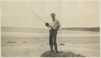 Man posed with fishing pole on rock