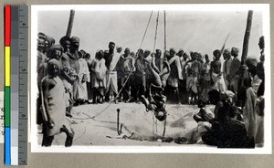 Hindu man hanging by his knees, swaying over a fire in front of observers to seek religious merit, Vārānasi , India, ca. 1920