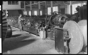 Interior view of unidentified factory, showing a single worker standing near the turbines, ca.1935