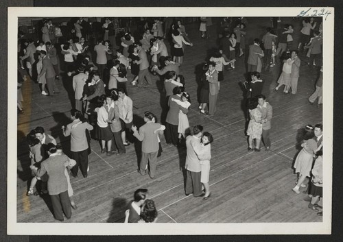 Dancing is one of the chief forms of recreation at the Heart Mountain Relocation Center. This scene in the High School Gymnasium shows the portion of the crowd at a school dance to which the public was invited. Photographer: Iwasaki, Hikaru Heart Mountain, Wyoming