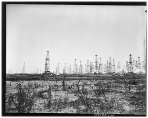 An oil field in the distance behind a grassy field
