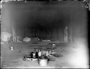 Interior of a Navajo hogan showing a fire in the center, ca.1900