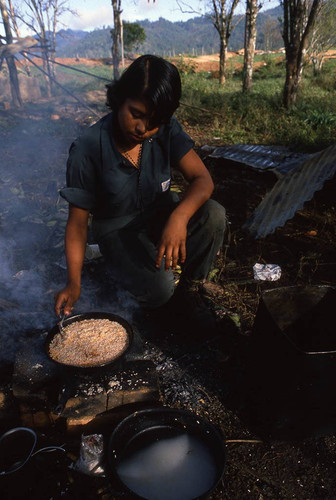 Young female Contra soldier cooks rice, Nicaragua, 1983