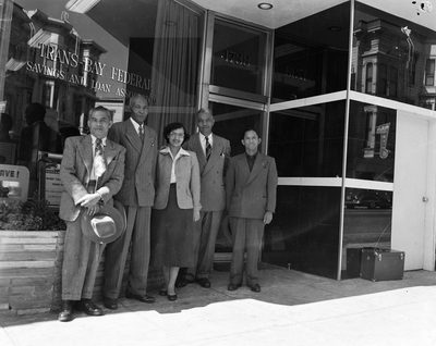 Four men and a woman standing in front of Trans-Bay Federal Savings and Loan Bank building