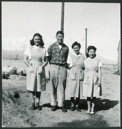 Photograph of four people standing in front of a utility pole with the Sierra Nevada in the background