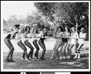 Five Playboy Bunnies in a tug of war with four women wearing sports clothing, ca.1960