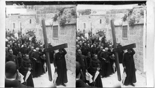 Devout pilgrims carrying a great cross thru the Via Dolorosa, Jerusalem. Palestine