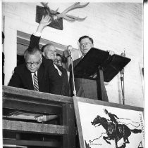 Postmaster General Arthur E. Summerfield, Sacramento Postmaster, Kenneth Hammaker (waving) and Federal Judge Sherrill Halbert at the podium for the dedication of the Pony Express stamp.T