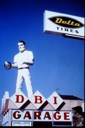DBI Garage with an oversized advertising manikin on the roof holding a tire, 1977