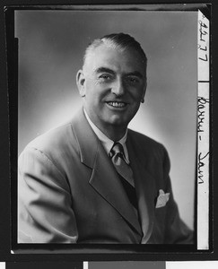 University of Southern California assistant football coach Sam Barry, posed in suit, striped tie, and handkerchief (smiling), 1949