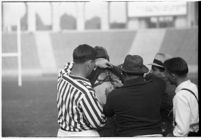 Loyola Lions' coach Tom Lieb and referees with player, during game against Santa Clara's Broncos at the Coliseum, Los Angeles, 1937