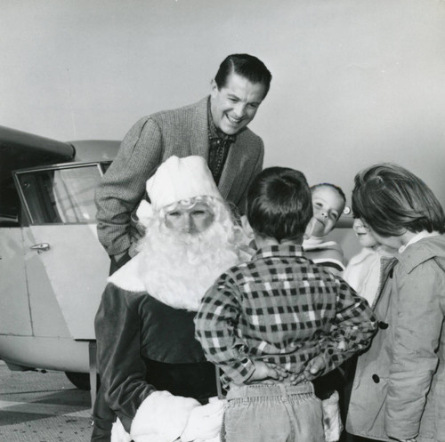 Merlyn Lund as Santa with children, Bob Cummins behind them in front of Bob's Ariocar at the International Airport