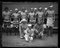 Indians from New Mexico in traditional clothing, holding rattles upon arrival at train station for Shriner convention in Los Angeles, Calif., 1925