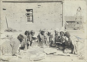 Girls grinding some limestone to clear the walls of the Morija school