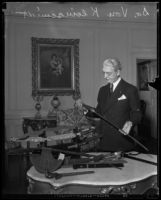 Dr. Rufus B. von Kleinsmid examines swords and other antique weapons, Los Angeles