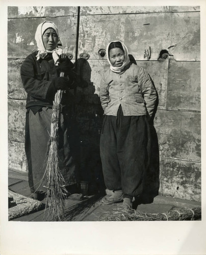 Two women standing with broom