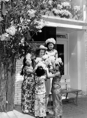 [Four young girls, dressed in costume, presenting daffodils to a woman on Maiden Lane]