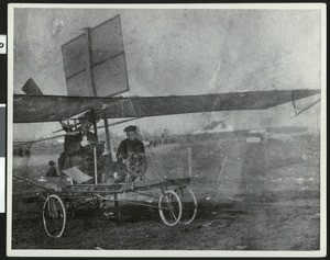 Man and a small child sitting in an early experimental plane, ca.1900