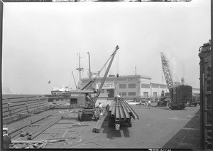 Dock scene at Los Angeles Harbor, showing steel beams being loaded on a truck, September 17, 1930