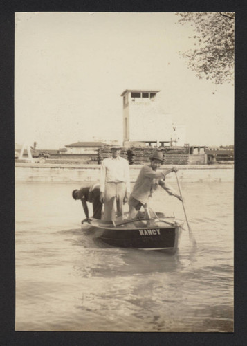 Three men paddling a boat in front of Vermont tower