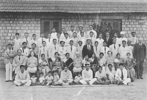 Lærere og studenter med deres familier på den Teologiske Præsteskole UTC i Bangalore, Sydindien 1948. På ve. fløj står skolens rektor, Dr. Harrison, på hø. fløj sprogskolens leder, Mr Jotimuttu. I midten ses sprogskolens husmor, Miss Van Dooren