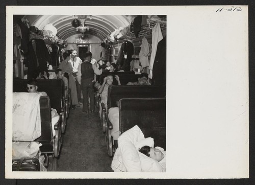 A scene in one of the twenty coaches on trip 15, Topaz to Tule Lake. The train monitor is seen conferring with a car captain and some of the passengers regarding the comfort of the latter. Photographer: Mace, Charles E