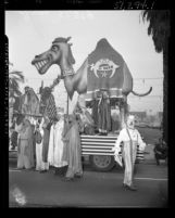 Shriners dressed in Arab robes with float in shape of a camel during Shriners convention parade in Los Angeles, Calif., 1950