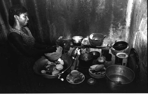 Woman washes dishes inside a house, San Basilio de Palenque, 1975