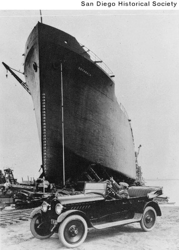 Two men in an automobile near the concrete ship Cuyamaca which was under construction at the Pacific Marine Construction Company