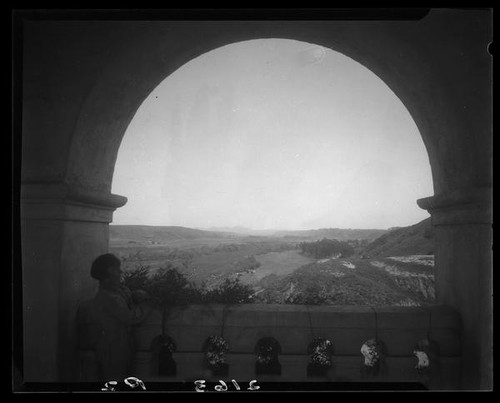 Mission San Diego de Alcalá, girl looking towards landscape from within archway, san Diego, 1931