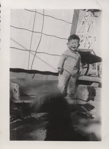 Laughing boy toddler standing on wooden bench at Poston incarceration camp