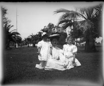 Woman with two children, on grass with palm trees