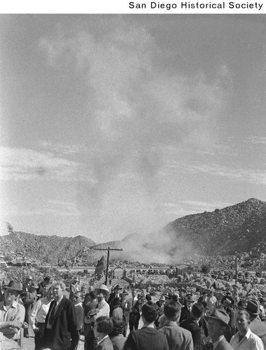 Group of people watching a plume of dust from a charge of dynamite