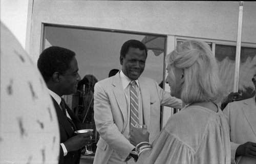 Sidney Poitier and Dr. Peter Bright-Asare greeting an unidentified woman, Los Angeles, 1983