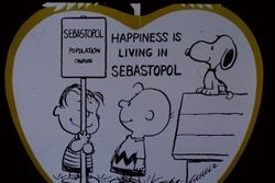 Advertisement sign drawn by Charles Schulz of Peanuts characters with caption "Happiness if living in Sebastopol, California," November 1971