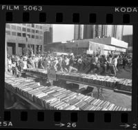 Crowd dashing to tables laden with books at Los Angeles Public Library's book sale, 1976