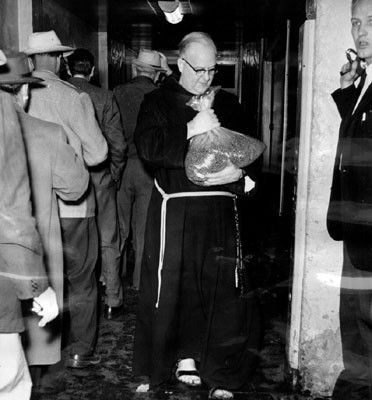[Father Alfred Boeddeker holding bag containing 25,000 pills]