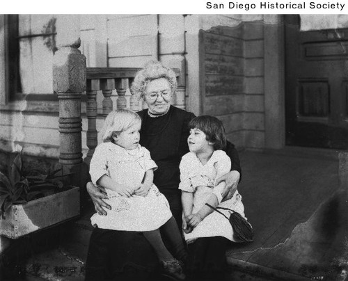 Two small children sitting on the lap of a woman at the Helping Hand Home in Golden Hill