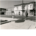 Man carrying groceries at the corner of 98th Avenue and East 14th Street in the Elmhurst district of Oakland, California