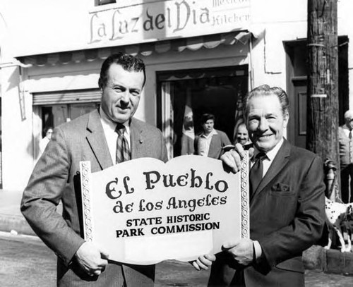 Hubert Laugharn holding the "El Pueblo..." sign with Mayor Yorty