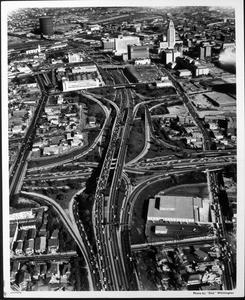 An aerial view of downtown Los Angeles, looking southeast over the intersection of the I-101 and I-110 Freeways toward City Hall and Union Station, 1964