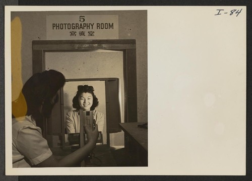 Yuki Shirakawa, Relocation Department Photographer, is taking a picture of Mrs. Robert Yoshio Kodama for the file and identification card
