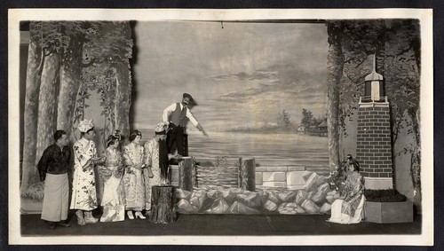 Man in Western attire points to the water, six figures look on, staged at the Great Star Theatre /