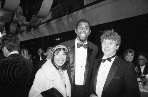 Magic Johnson posing with a couple at the American Music Awards, Los Angeles, 1983