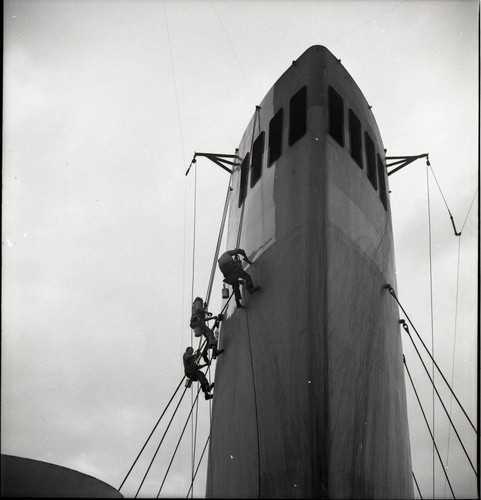 Men painting a smokestack on the USS Meigs