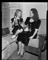 Mrs. Russell Smith and Lynn Helm play with toys while modeling winter fashion, Los Angeles, 1938