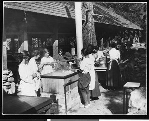 Women cooking outdoors near a pavilion, ca.1930