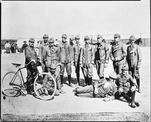 Portrait of the 11 Los Angeles Wheelmen posing as a group in cadet type uniforms at the East Side (Boyle Heights) track, October 3, 1893