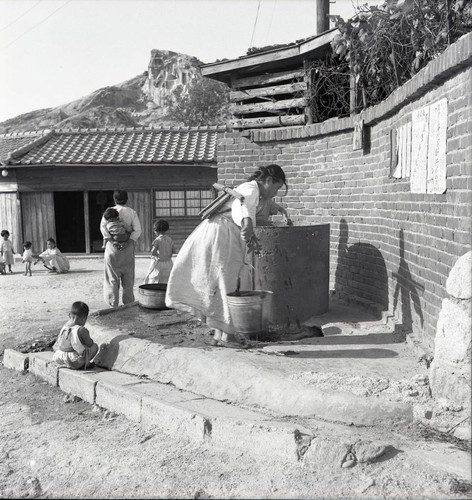 Woman getting water from a well in town